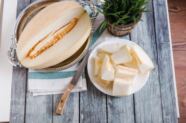 Natürmort bıçak, peçete ve vazo arka plan üzerinde beyaz tabakta servis taze kesilerek kavun ile