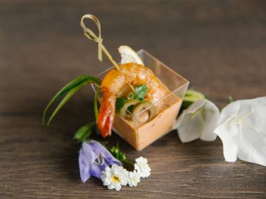 Cam vazo içinde tropikal sos ve arka plan üzerinde çiçekli zeytin ile servis şiş karides closeup görünümü