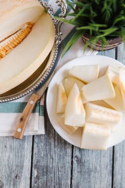 Natürmort bıçak, peçete ve vazo arka plan üzerinde beyaz tabakta servis taze kesilerek kavun ile