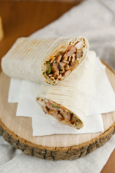 Appetizing shawarma on sawed wood with linen napkin and blurred background