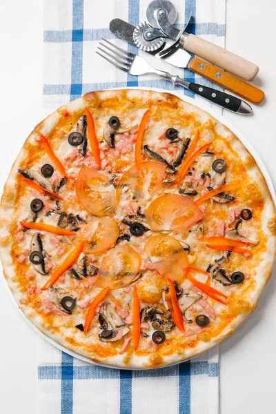 Pizza with cutlery, pizza cutter, spatula and checkered napkin