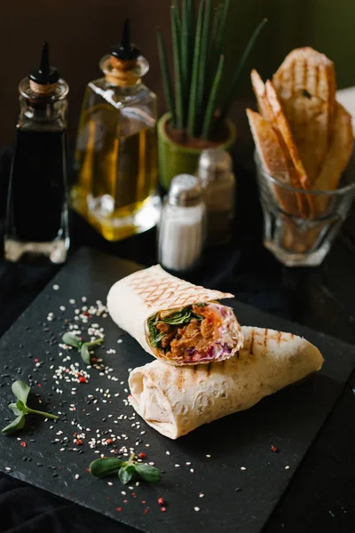 siyah tabakta shaverma iki adet tamamlanmaktadır germinated ayçiçeği tohumu ve sezame ve zeytin yağı, balsamik sosu, tuz, biber, zemin üzerine vazo ile