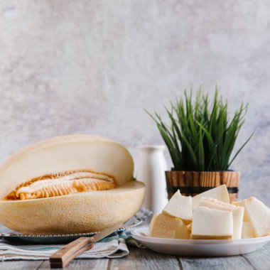 Natürmort bıçak, çizgili peçete, beyaz şişe ve arka plan üzerinde vazo ile kesilerek kavun ile