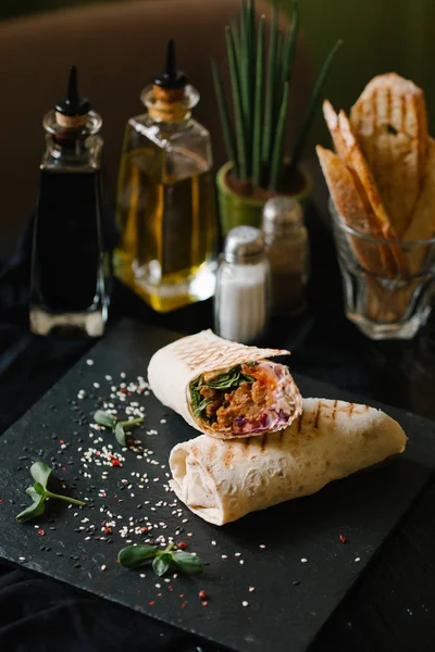 siyah tabakta shaverma iki adet tamamlanmaktadır germinated ayçiçeği tohumu ve sezame ve zeytin yağı, balsamik sosu, tuz, biber, zemin üzerine vazo ile