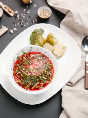 Borsch haşlanmış patates ve dereotu ile keten peçete beyaz tabakta ve baharat arka plan üzerinde