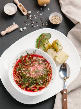 Borsch haşlanmış patates ve dereotu ile keten peçete beyaz tabakta ve baharat arka plan üzerinde