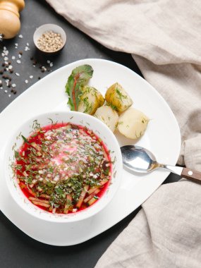 Borsch haşlanmış patates ve dereotu ile keten peçete beyaz tabakta ve baharat arka plan üzerinde