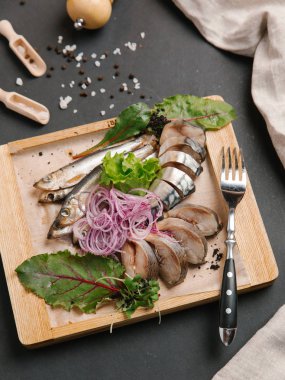 Ahşap doğrama tahtası üzerinde soğan bobinleri ile servis scomber dilimlenmiş