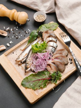 Ahşap doğrama tahtası üzerinde soğan bobinleri ile servis scomber dilimlenmiş