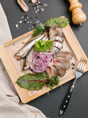 Ahşap doğrama tahtası üzerinde soğan bobinleri ile servis scomber dilimlenmiş