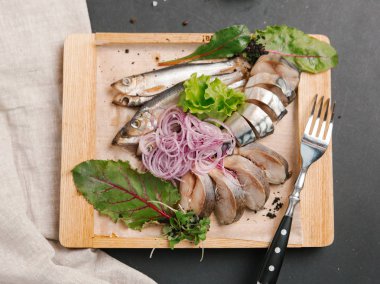 Ahşap doğrama tahtası üzerinde soğan bobinleri ile servis scomber dilimlenmiş