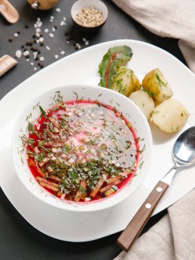 Borsch haşlanmış patates ve dereotu ile keten peçete beyaz tabakta ve baharat arka plan üzerinde