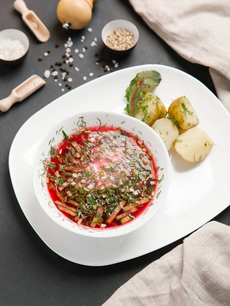 Borsch haşlanmış patates ve dereotu ile keten peçete beyaz tabakta ve baharat arka plan üzerinde