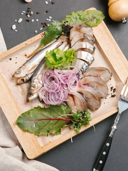 Ahşap doğrama tahtası üzerinde soğan bobinleri ile servis scomber dilimlenmiş