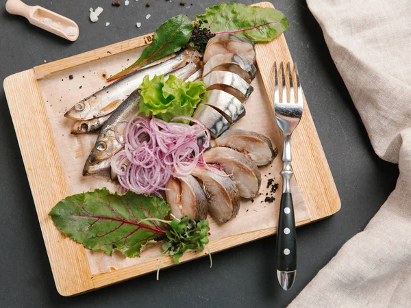 Ahşap doğrama tahtası üzerinde soğan bobinleri ile servis scomber dilimlenmiş