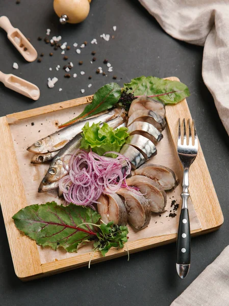 Ahşap doğrama tahtası üzerinde soğan bobinleri ile servis scomber dilimlenmiş