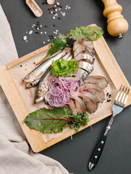 Ahşap doğrama tahtası üzerinde soğan bobinleri ile servis scomber dilimlenmiş