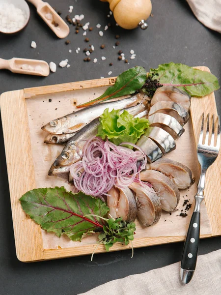 Ahşap doğrama tahtası üzerinde soğan bobinleri ile servis scomber dilimlenmiş