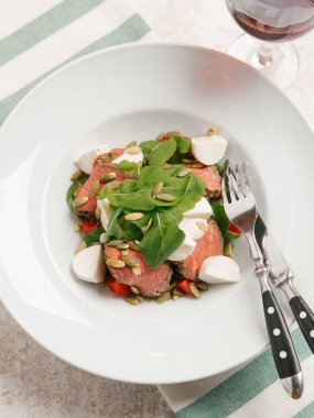 Mozzarella peyniri, domates, ıspanak ve çizgili peçete üzerinde kabak çekirdeği ile servis sığır eti adet pişmiş 