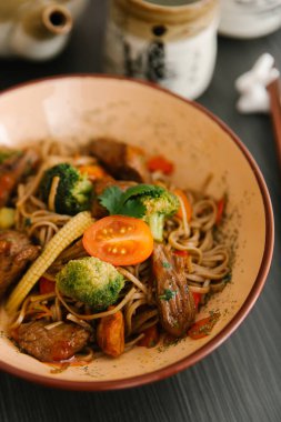 Brokoli, Bebek Mısır ve domuz eti ve masada kapta domates ile Asya erişte