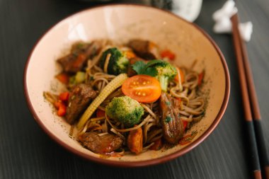 Brokoli, Bebek Mısır ve domuz eti ve masada kapta domates ile Asya erişte