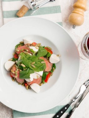 Mozzarella peyniri, domates, ıspanak ve çizgili peçete üzerinde kabak çekirdeği ile servis sığır eti adet pişmiş 