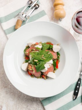 Mozzarella peyniri, domates, ıspanak ve çizgili peçete üzerinde kabak çekirdeği ile servis sığır eti adet pişmiş 