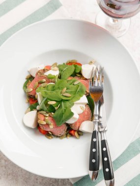 Mozzarella peyniri, domates, ıspanak ve çizgili peçete üzerinde kabak çekirdeği ile servis sığır eti adet pişmiş 