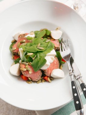 Mozzarella peyniri, domates, ıspanak ve çizgili peçete üzerinde kabak çekirdeği ile servis sığır eti adet pişmiş 