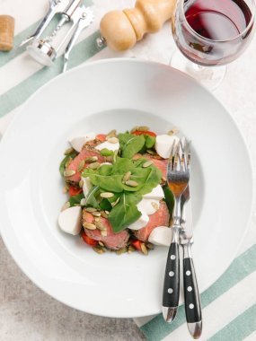 Mozzarella peyniri, domates, ıspanak ve çizgili peçete üzerinde kabak çekirdeği ile servis sığır eti adet pişmiş 