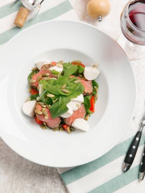 Mozzarella peyniri, domates, ıspanak ve çizgili peçete üzerinde kabak çekirdeği ile servis sığır eti adet pişmiş 