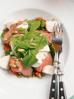 Mozzarella peyniri, domates, ıspanak ve çizgili peçete üzerinde kabak çekirdeği ile servis sığır eti adet pişmiş 