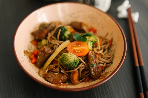 Brokoli, Bebek Mısır ve domuz eti ve masada kapta domates ile Asya erişte