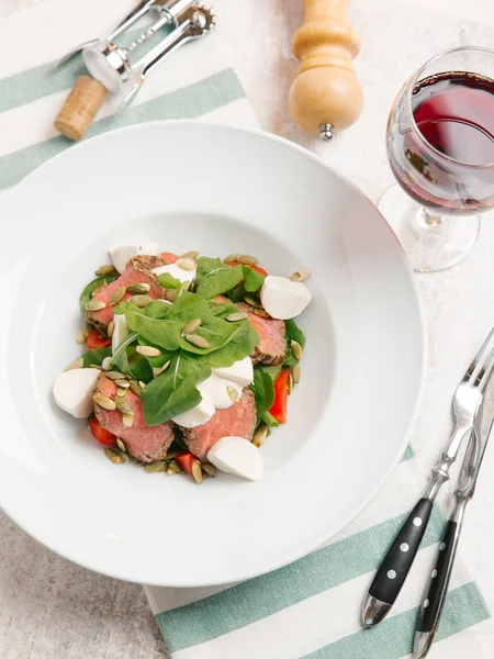 Mozzarella peyniri, domates, ıspanak ve çizgili peçete üzerinde kabak çekirdeği ile servis sığır eti adet pişmiş 