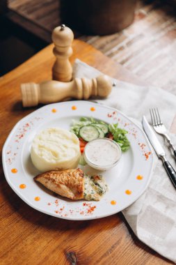 Patates püresi ve sebze ile beyaz tabakta sos ile ızgara tavuk kapatın. Keten peçete ile ahşap tablo