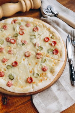 Salam ve salatalık lezzetli pizza görünümü keten peçete ve çatal bıçak ile ahşap trencher üzerinde kapat