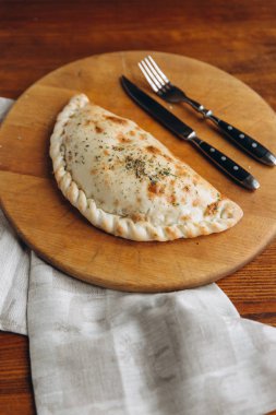 Bıçak ve çatal ile calzone ahşap tahta üzerinde kapat