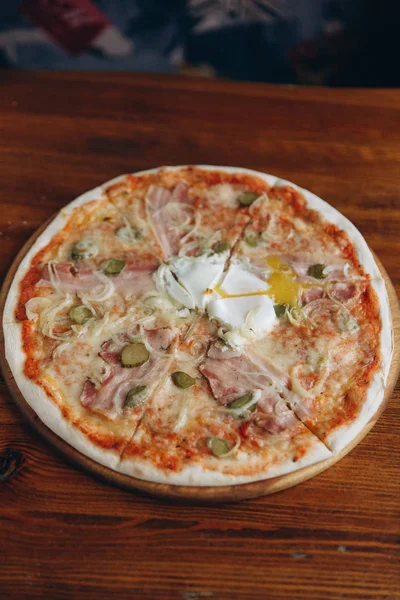 Tasty meat pizza with white sauce on wooden table surface
