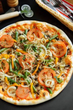 Peynirli pizza soğan, mantar, kabuk fasulye ve beyaz tabakta domates