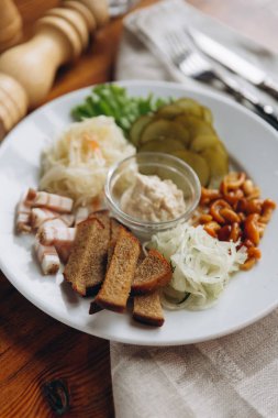 Closeup plaka atıştırmalıklar ile görüntülemek ve orta ve karabiber değirmeni, çatal bıçak takımı bej peçeteye ayarla sos