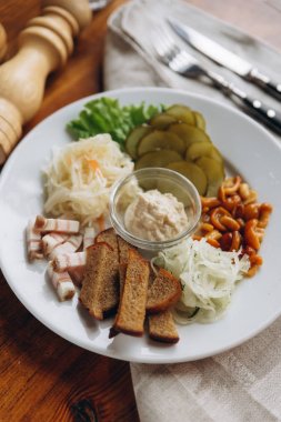 Closeup plaka atıştırmalıklar ile görüntülemek ve orta ve karabiber değirmeni, çatal bıçak takımı bej peçeteye ayarla sos