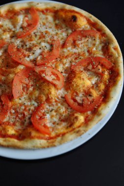 Beyaz tabakta dilimlenmiş domates, sos ve peynir İtalyan pizza Margherita Görünümü Kapat.