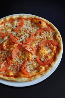 Beyaz tabakta dilimlenmiş domates, sos ve peynir İtalyan pizza Margherita Görünümü Kapat.
