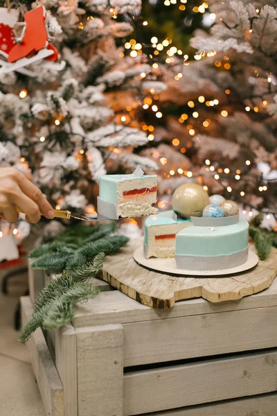 Splited Christmas cake with jello and souffle with piece of cake in air with fir and lights on background