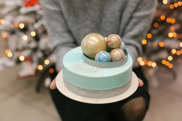 Christmas cake with chocolate balls on top in female hands