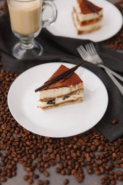 Doğum günü pastası beyaz tabak, kahve çekirdekleri, çatal ve peçete ile kompozisyon