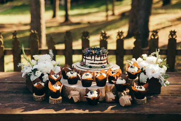 背景にぼやけフォレストと木の切り株にベリーのケーキとブルーベリーとローズマリー風味のカップケーキのフロント ビュー — ストック写真