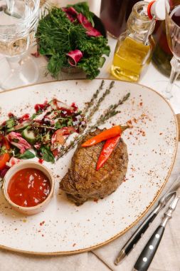 kaburga eti beyaz tabakta salata ve domates soslu