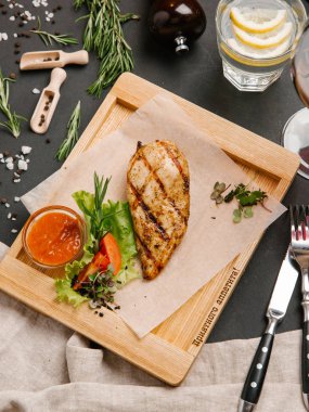 Domates soslu ızgara tavuk göğsü üzerinde ahşap kurulunda görev yapmaktadır.