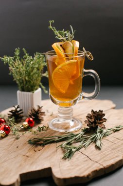 Portakal, limon dilimleri ve Noel topları, çam kozalakları ve biberiye şube ile dekore edilmiş bal da dahil olmak üzere şenlikli içecek sawed tahtaya hizmet